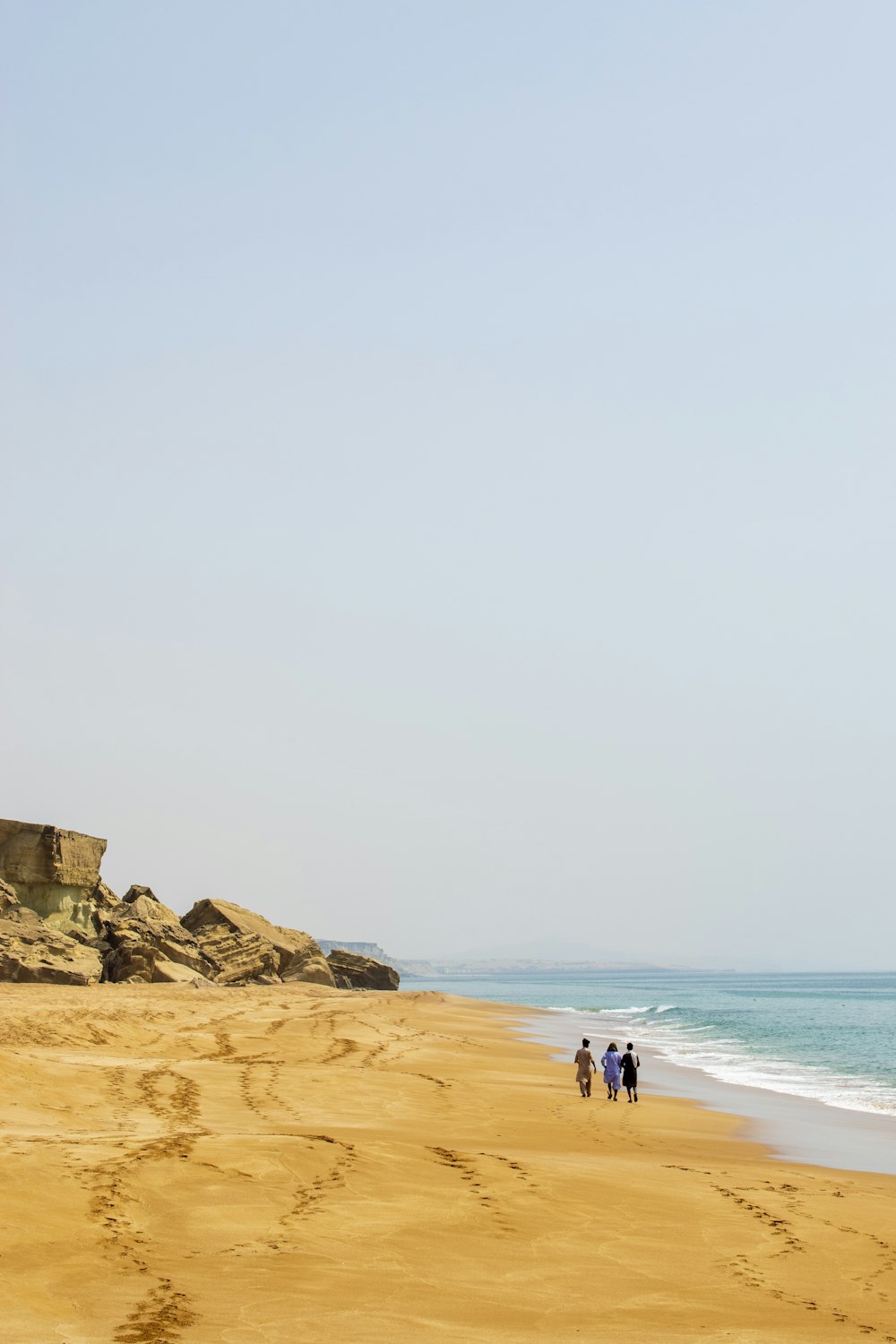un groupe de personnes marchant le long d’une plage de sable