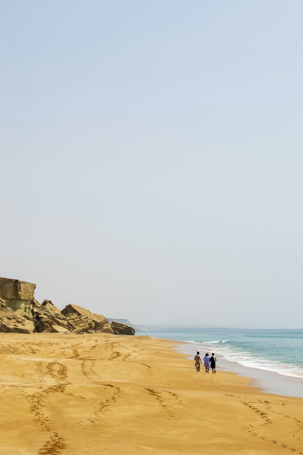 a group of people walking along a sandy beach