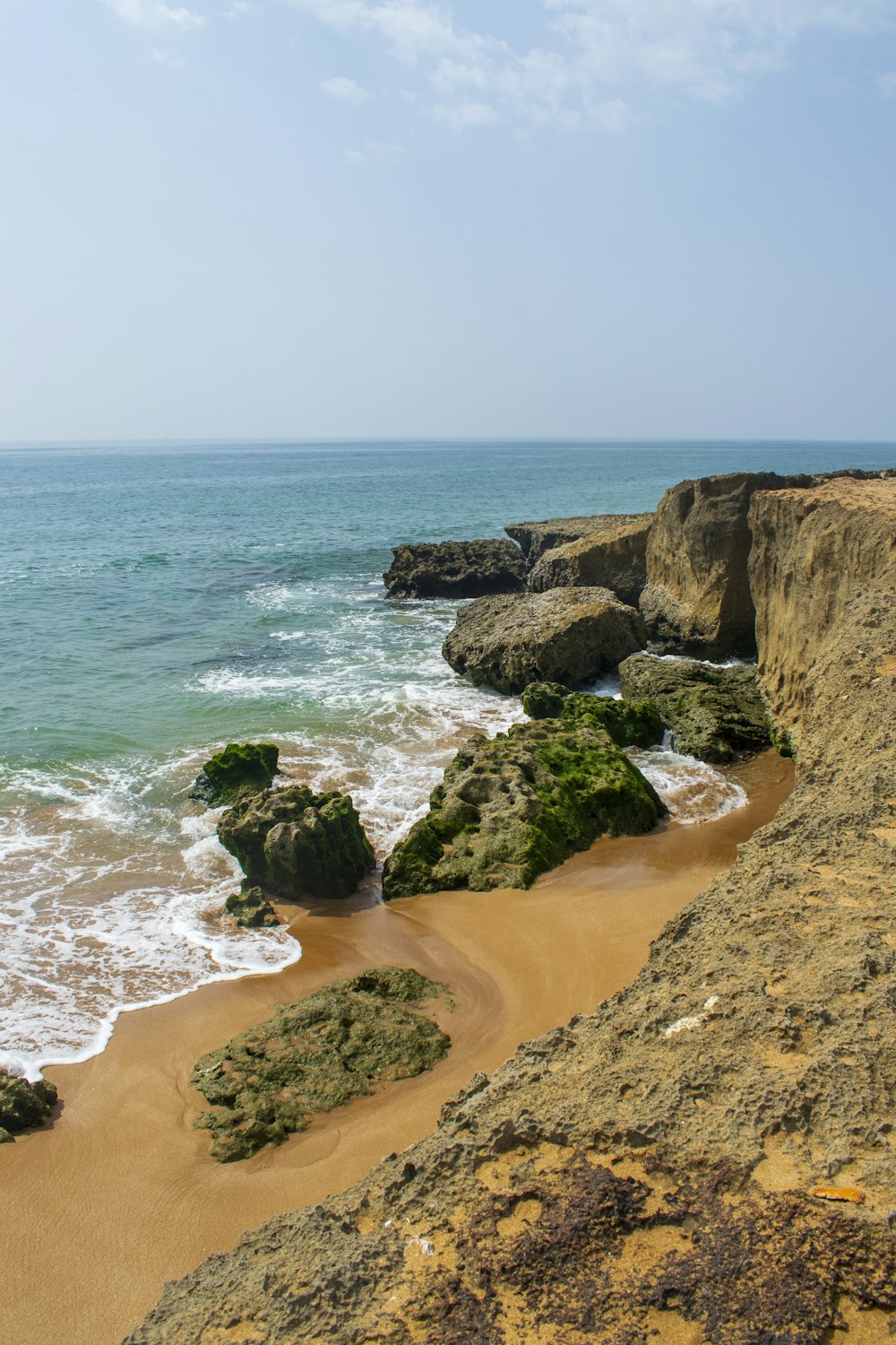 a sandy beach next to the ocean under a blue sky