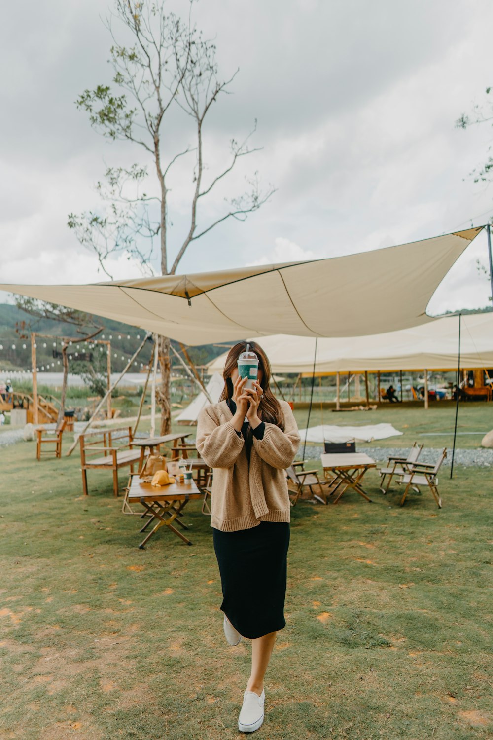 a woman taking a picture of herself in front of a tent