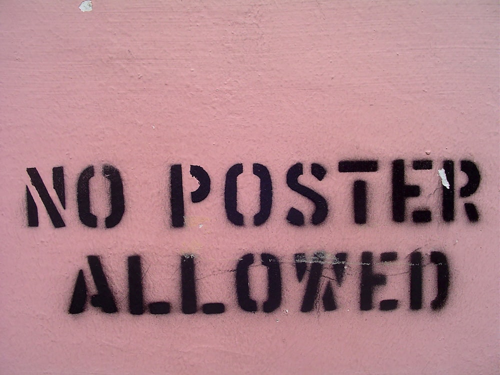 a sign that says no poster allowed on a pink wall