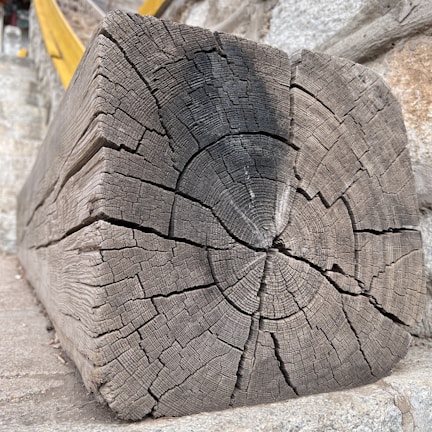 Side-by-side images displaying a weathered wooden beam transformed by aerogommage.