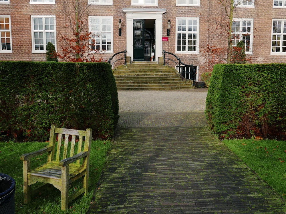 a wooden bench sitting in front of a tall brick building