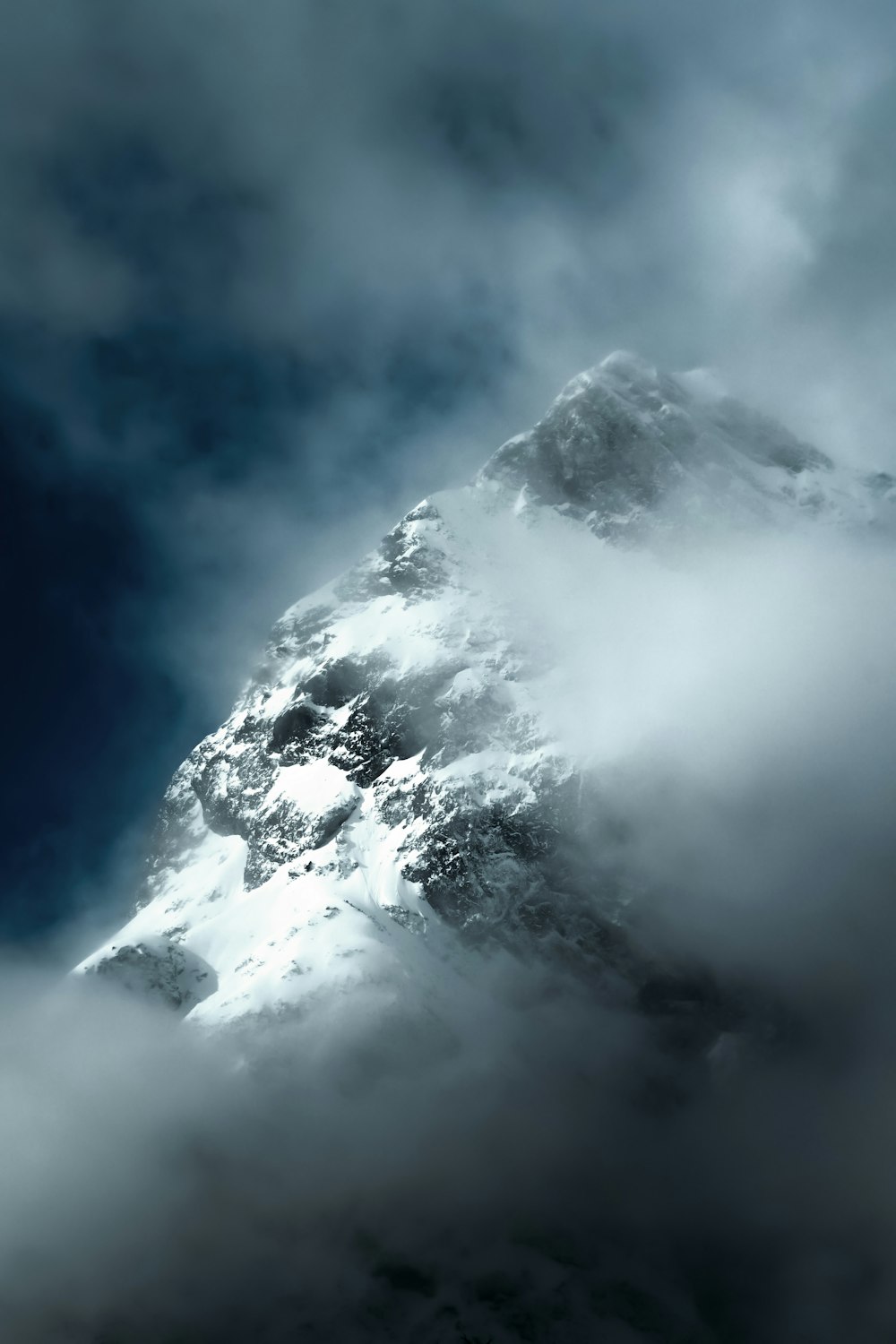 Une très haute montagne couverte de nuages sous un ciel bleu