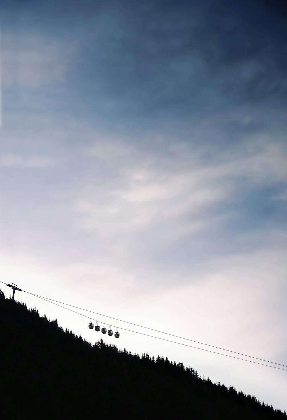 uma pessoa em pé no topo de uma colina com um teleférico de esqui ao fundo