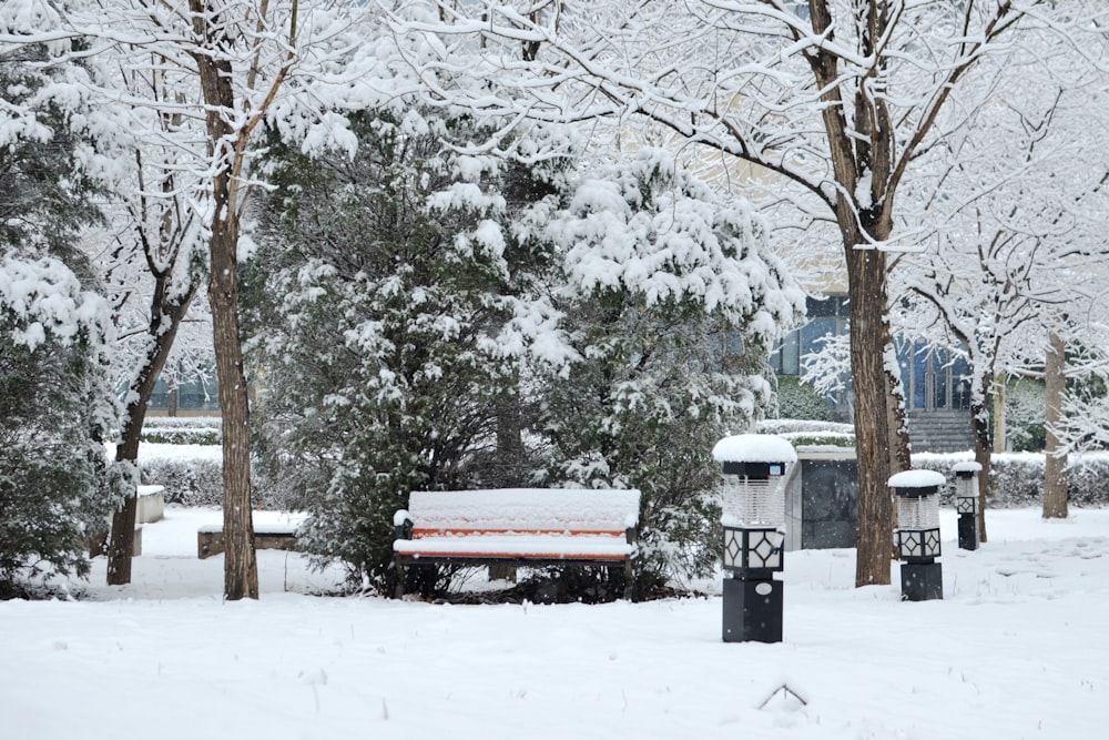 a park bench covered in snow next to trees