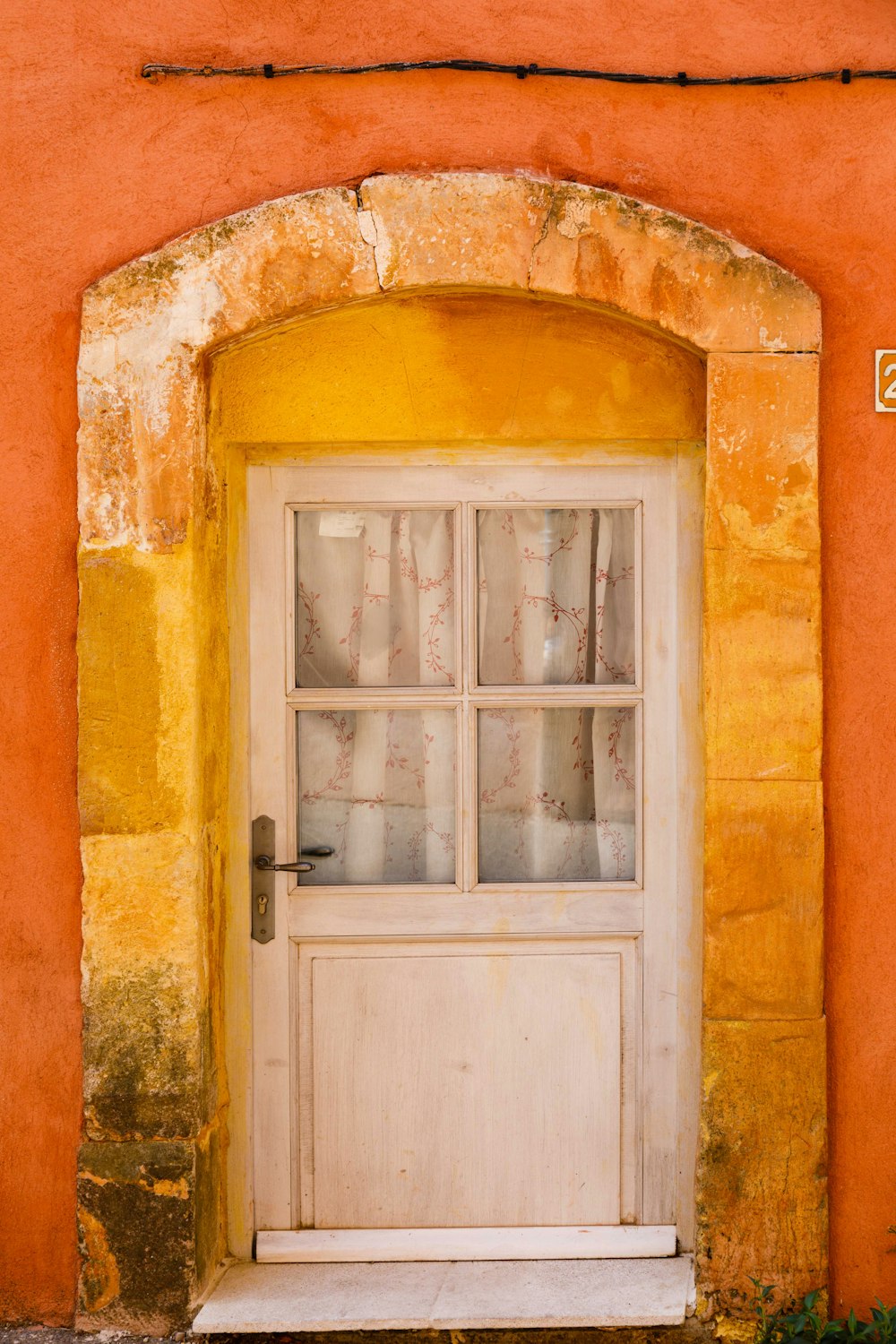 a white door with a window on a yellow wall