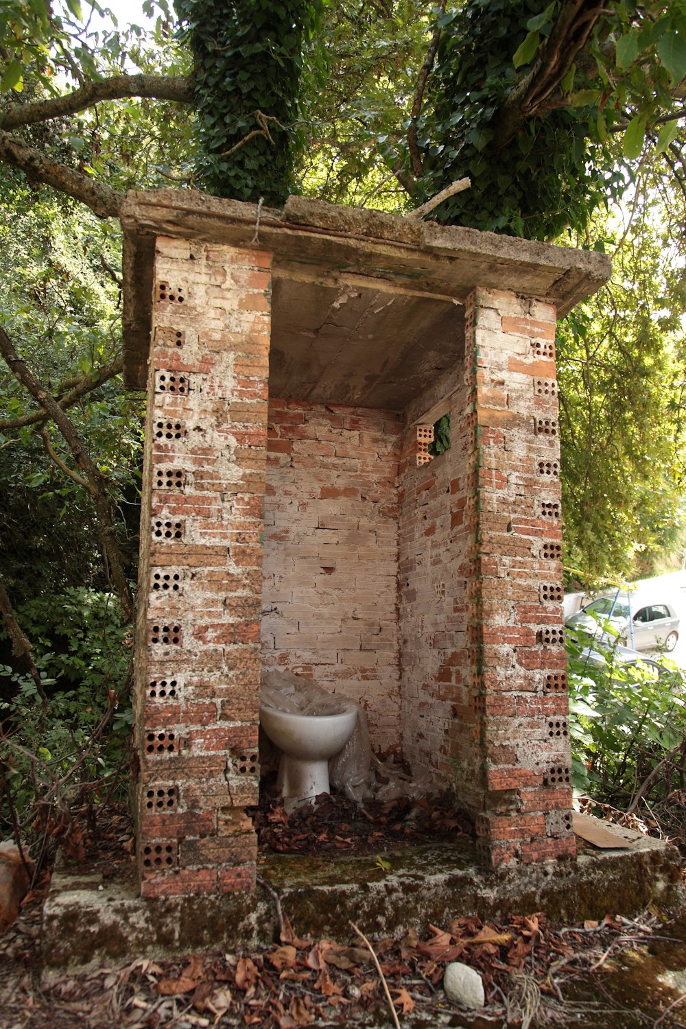 a toilet in a brick structure surrounded by trees