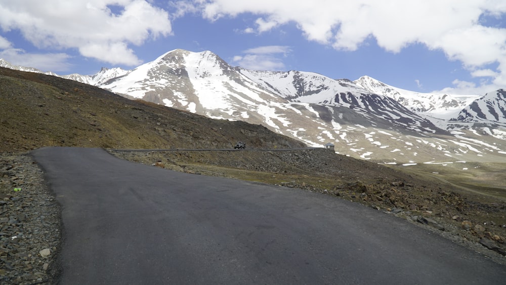 a road going up a hill with snow covered mountains in the background