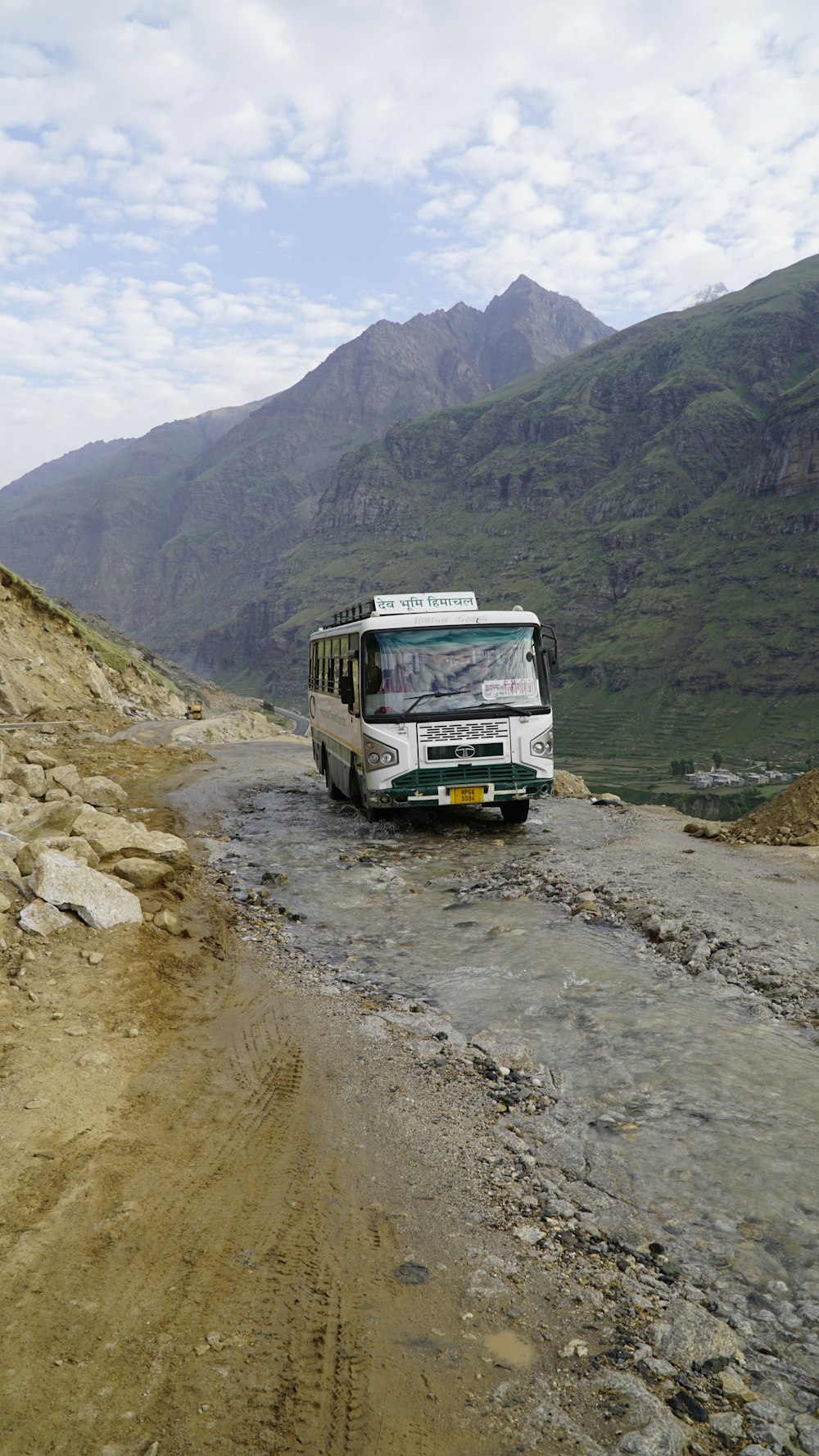 a bus driving down a dirt road in the mountains