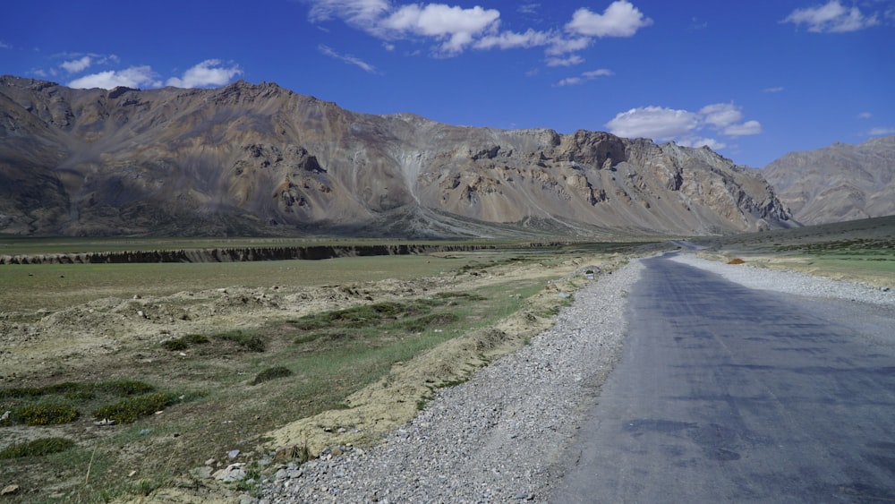 a gravel road in front of a mountain range