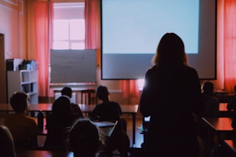 a woman standing in front of a classroom full of students