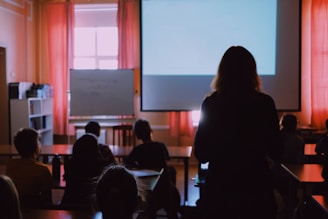 a woman standing in front of a classroom full of students
