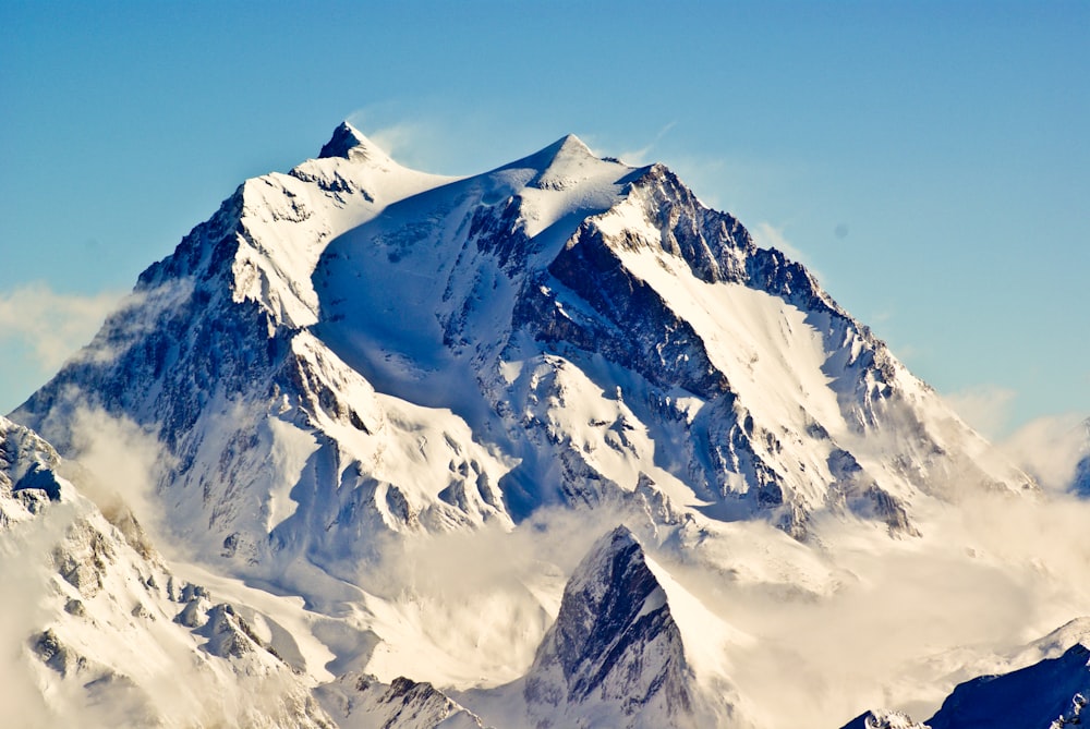 a large mountain covered in snow under a blue sky