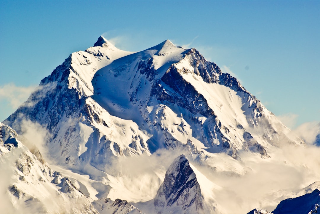 a large mountain covered in snow under a blue sky, The Alpine symphony