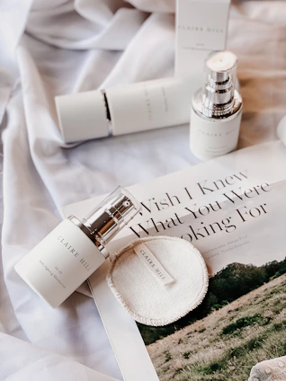 A serene flat lay of glowing skincare bottles and jars surrounded by fresh flowers and soft fabric