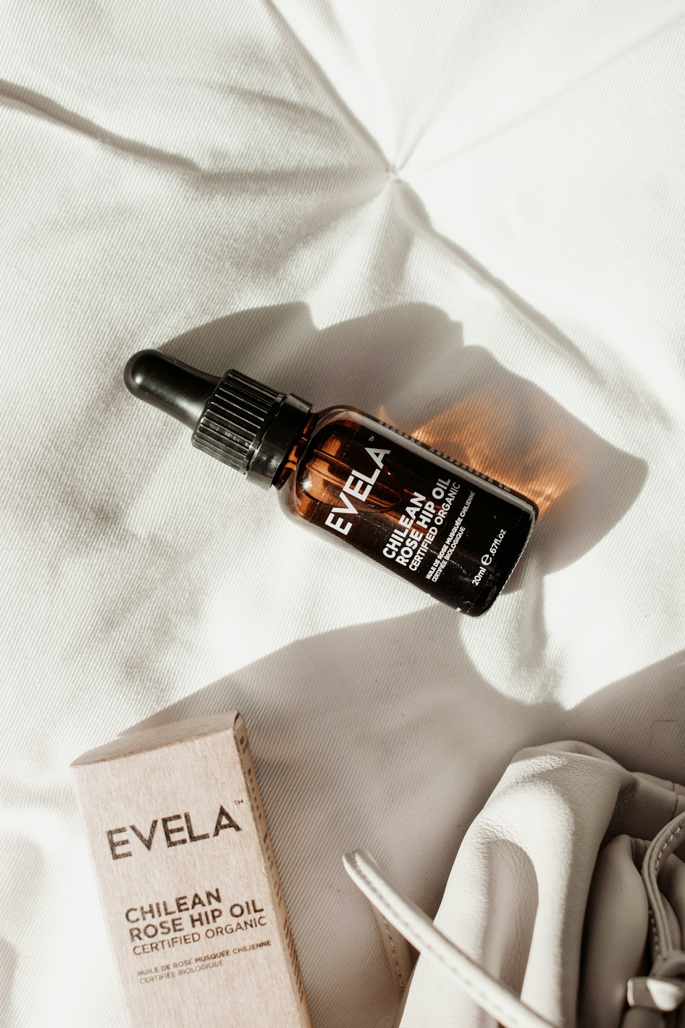 a bottle of eyela on a bed next to a box of eye cream