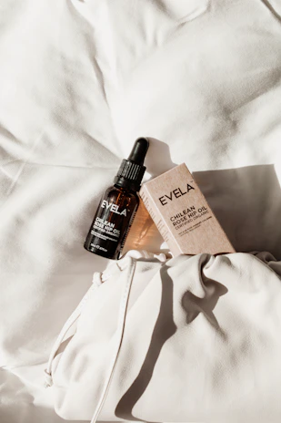 Elegant amber bottle of rosehip oil resting on soft beige linen with scattered rosehip fruits.