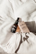 A bottle of Evelia Chilean Rose Hip Oil with a dropper sits atop a textured white fabric surface, alongside its packaging box. The items are positioned to capture natural light, creating soft shadows and highlighting the elegant presentation.