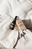 A bottle of Evelia Chilean Rose Hip Oil with a dropper sits atop a textured white fabric surface, alongside its packaging box. The items are positioned to capture natural light, creating soft shadows and highlighting the elegant presentation.