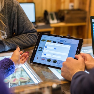 two people sitting at a table looking at a tablet