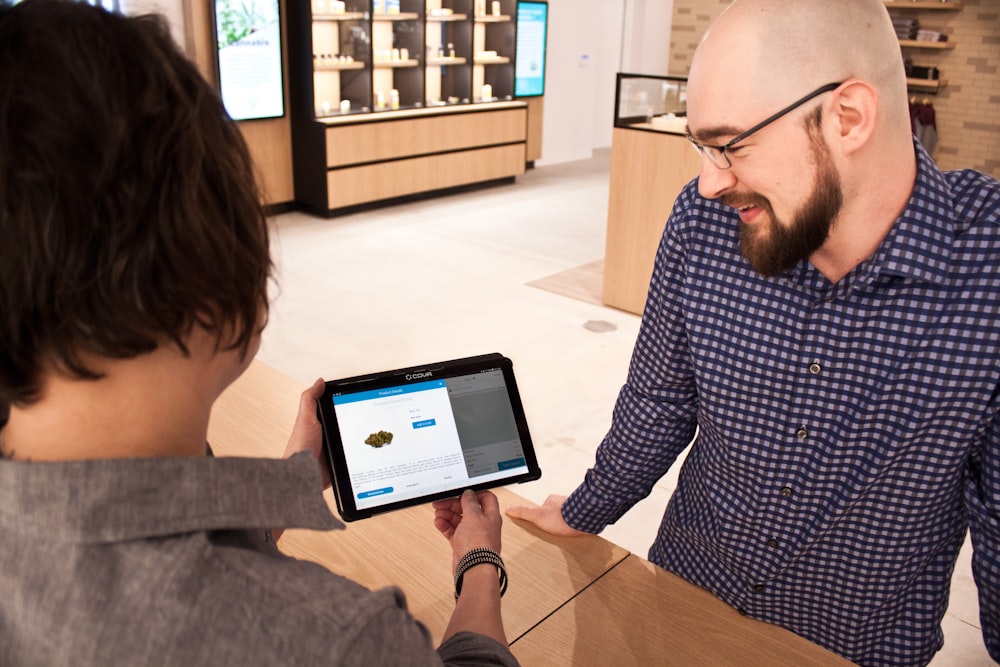 a man showing a tablet to a woman in a store