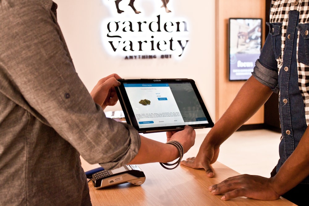 a man holding a tablet while standing next to another man