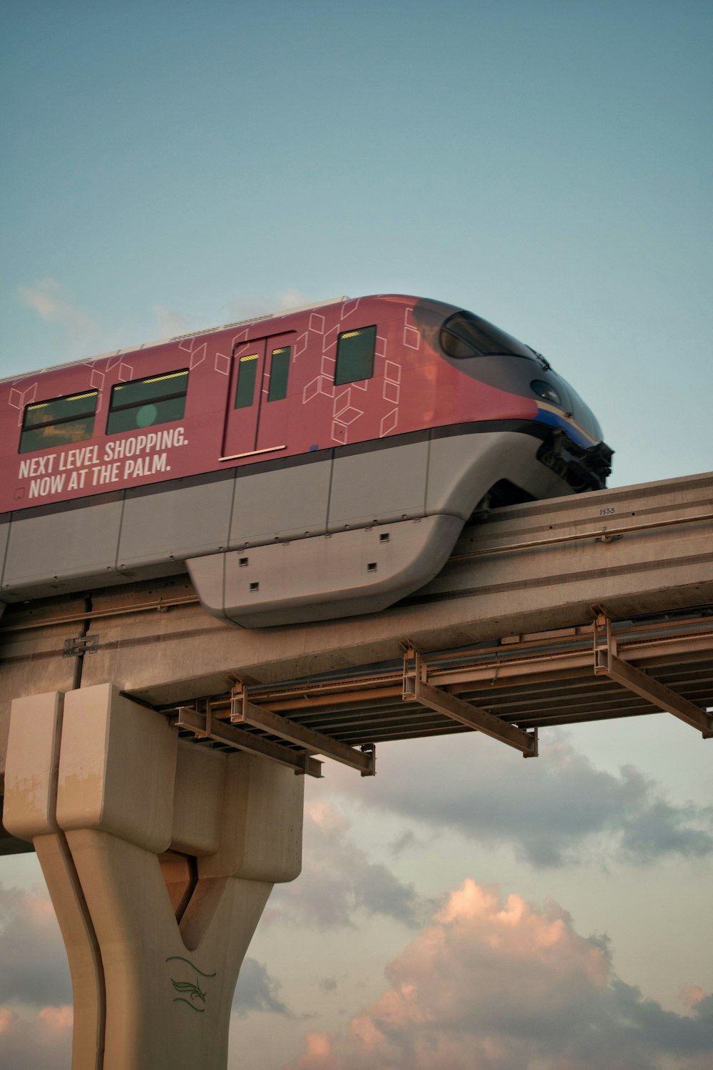 a red train traveling over a bridge under a cloudy sky