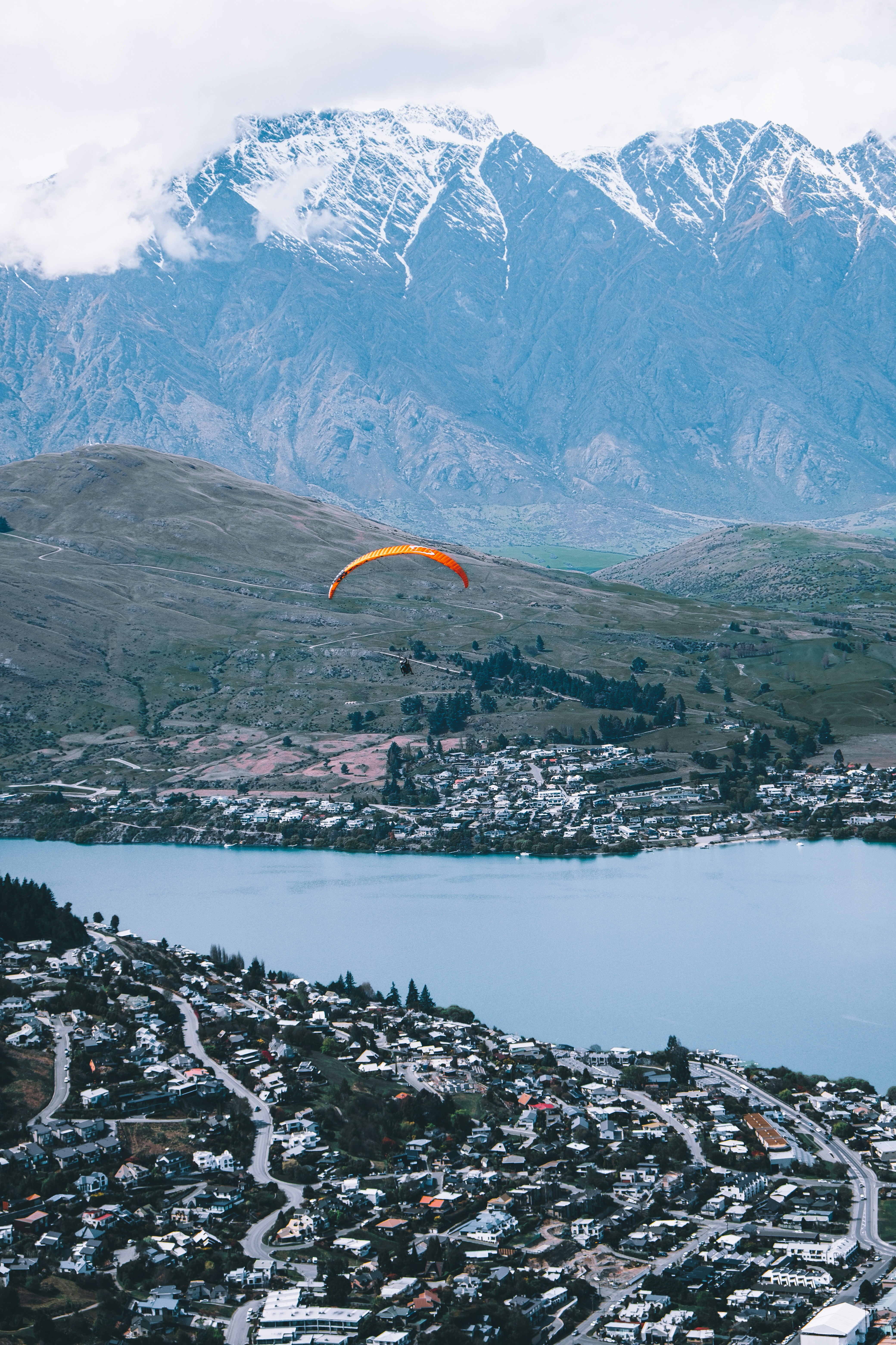 a paraglider flying over a city with mountains in the background