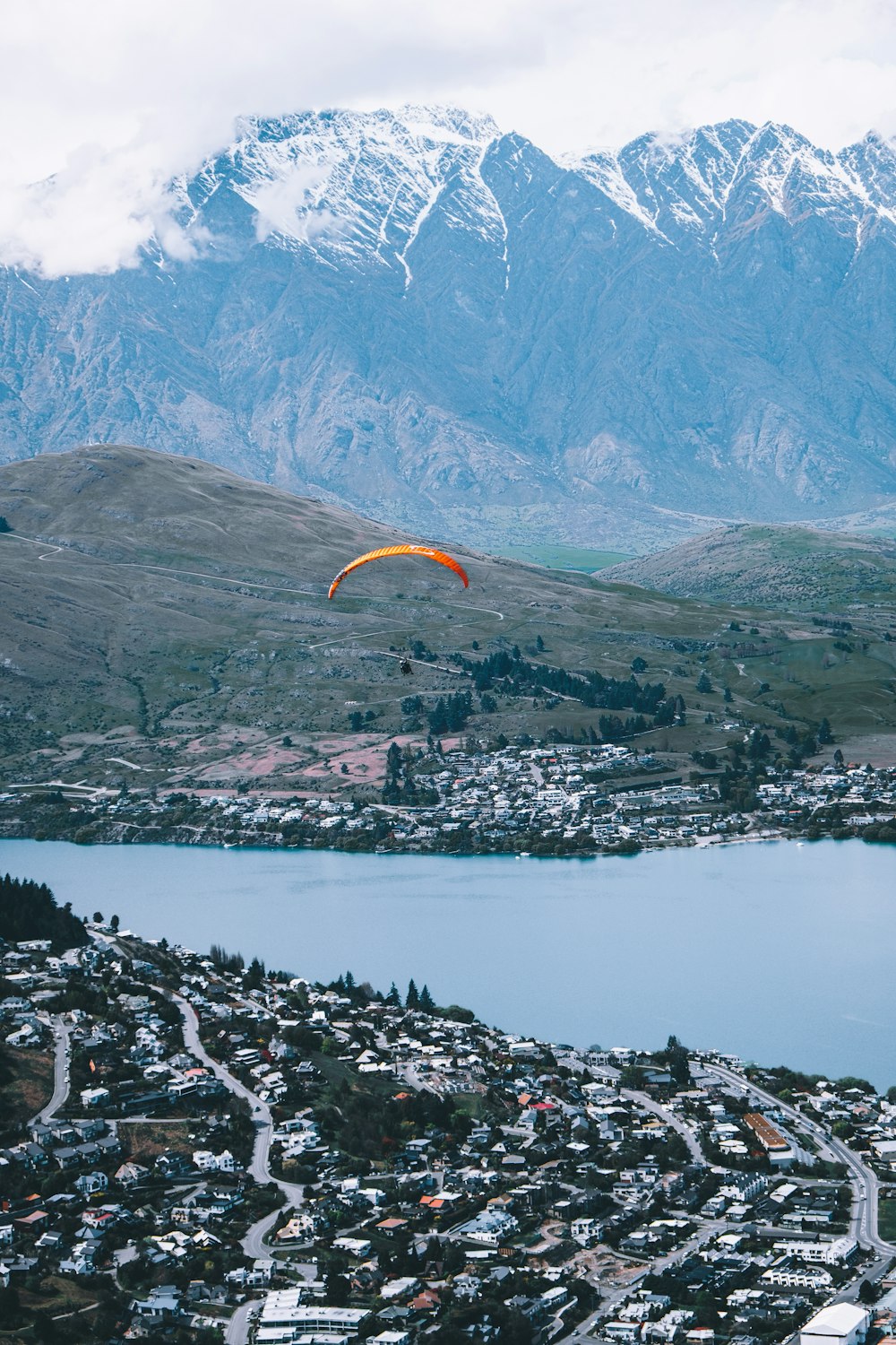 a paraglider flying over a city with mountains in the background