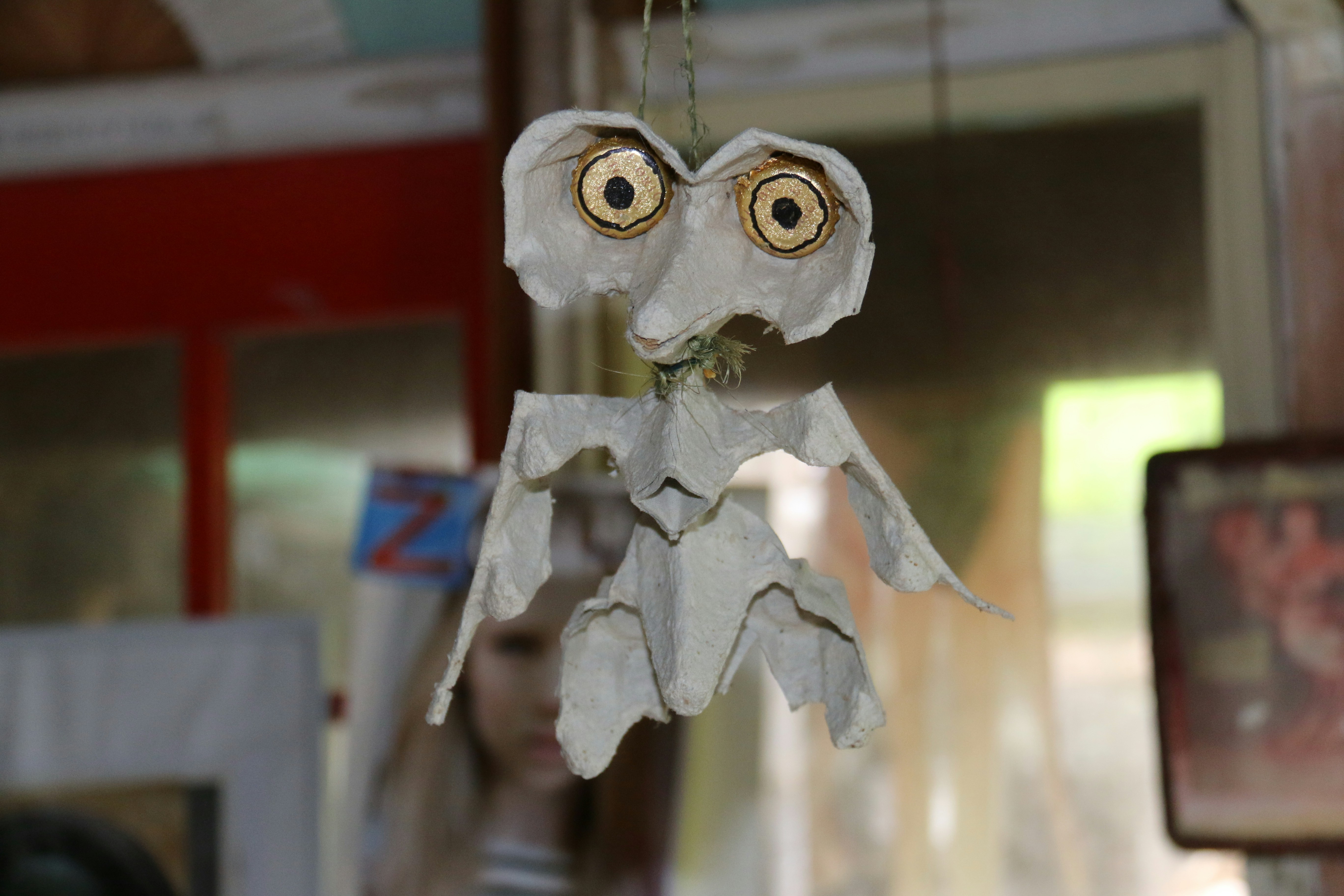 a close up of a paper doll hanging from a string