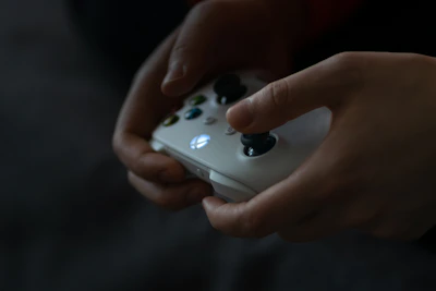 Gamer hands holding a controller with colorful LED lights in a dark room