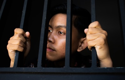 a man is looking out of a jail cell