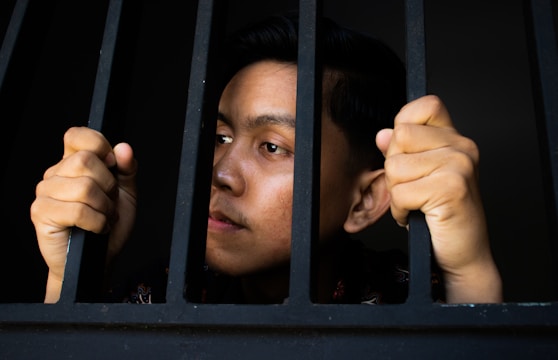 a man is looking out of a jail cell