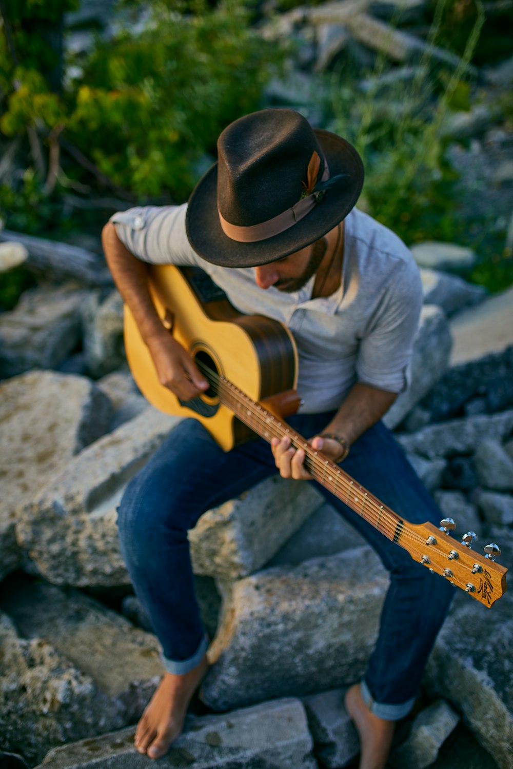 a man sitting on rocks playing a guitar