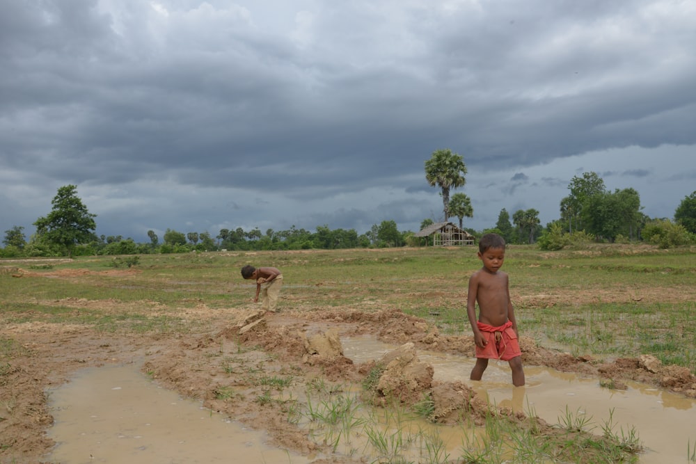 a young boy standing in a muddy field