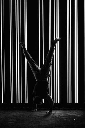 a man doing a handstand in front of a wall of lights