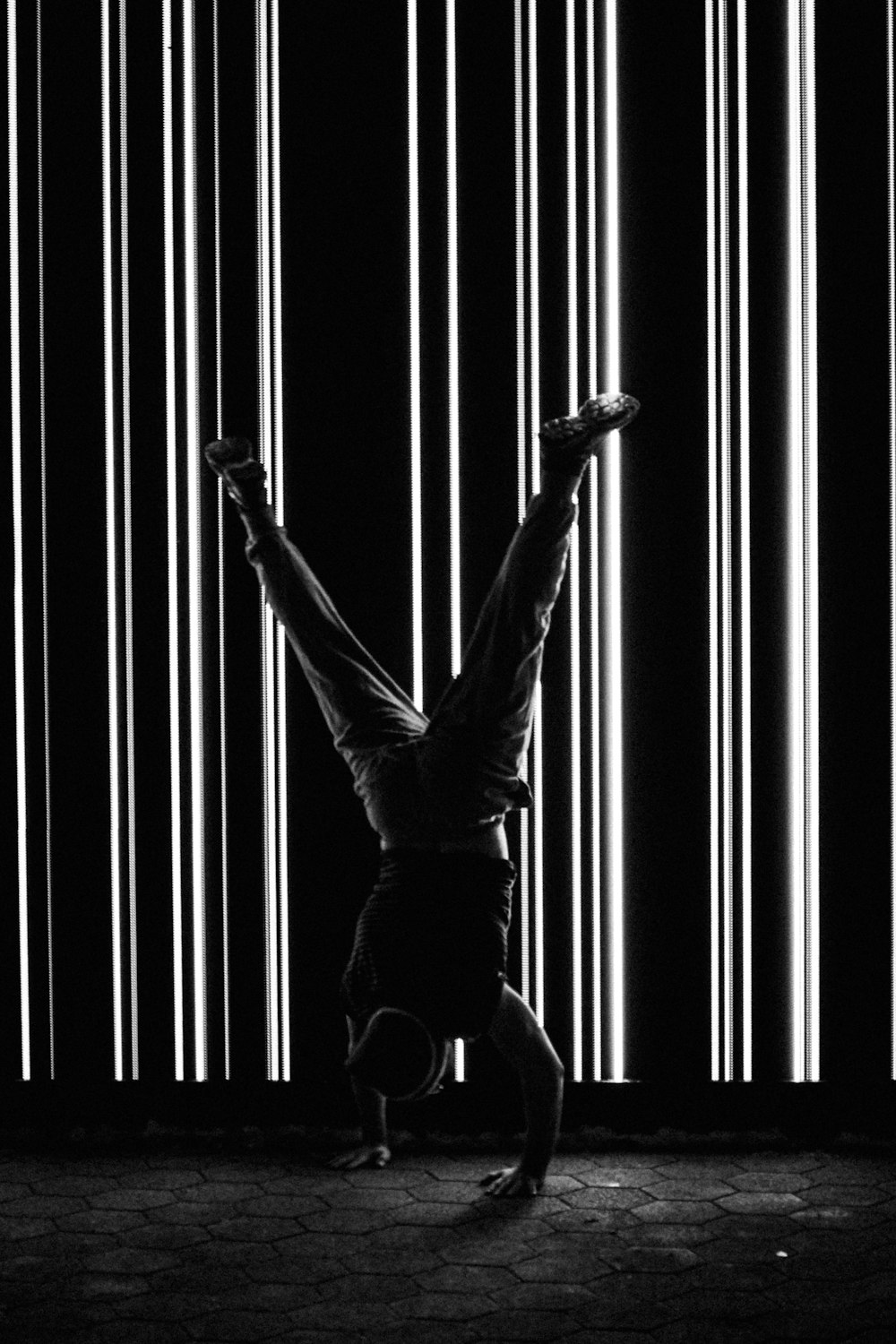 a man doing a handstand in front of a wall of lights