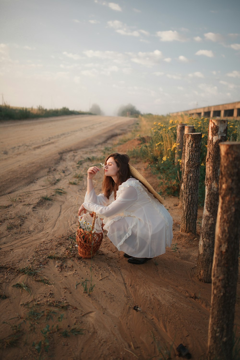 a woman sitting on the side of a dirt road