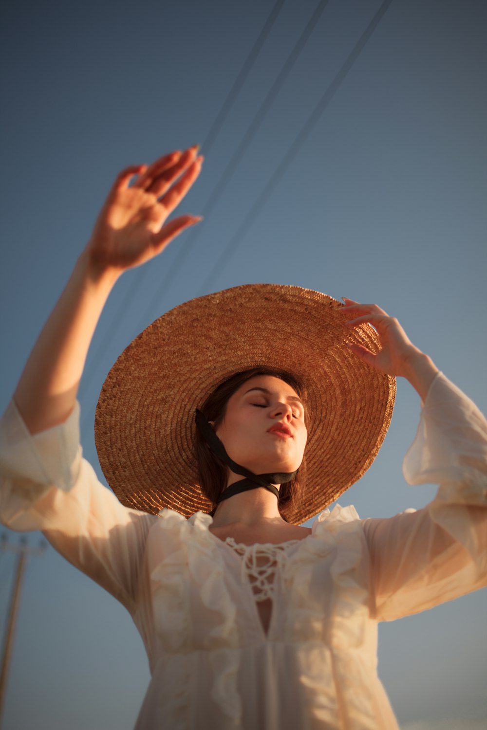 a woman wearing a straw hat and holding her hands up in the air