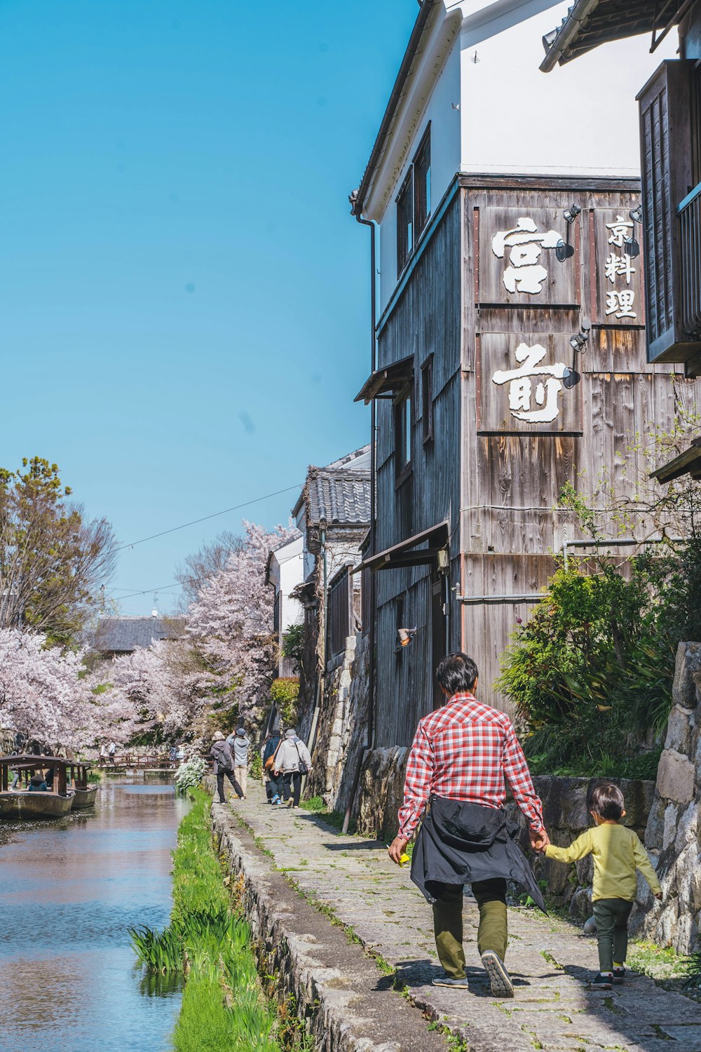 a woman and a child walking down a street next to a body of water