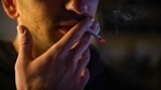 a man smoking a cigarette in the dark