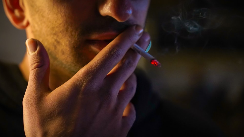 um homem fumando um cigarro no escuro