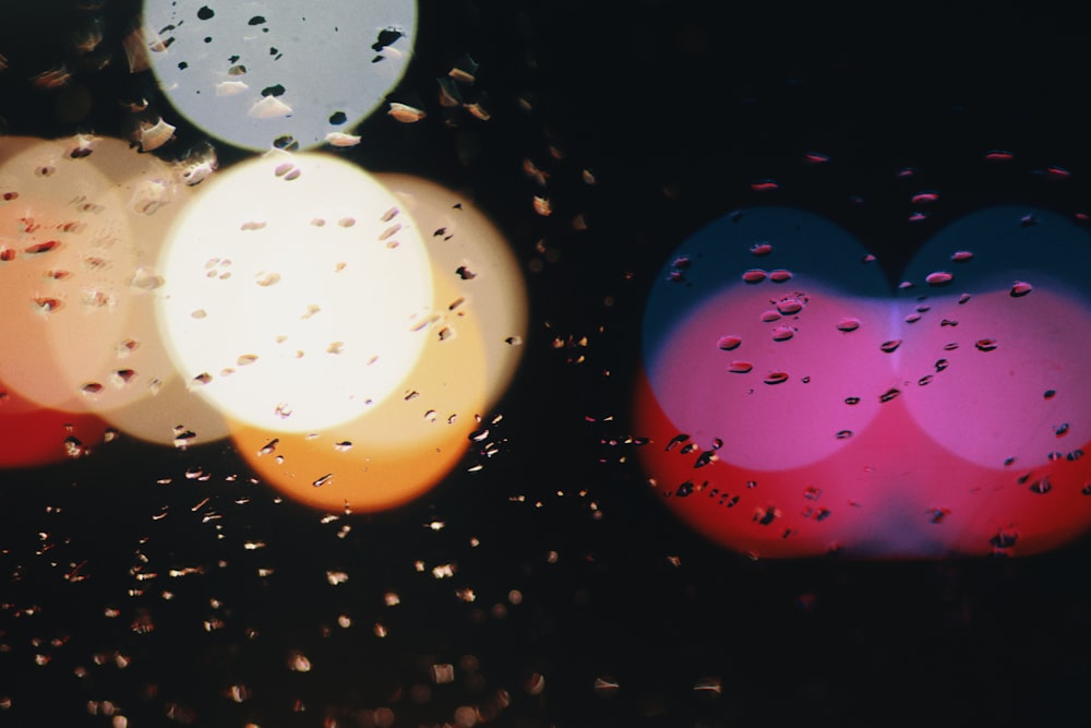rain drops on a window with a heart shaped light in the background