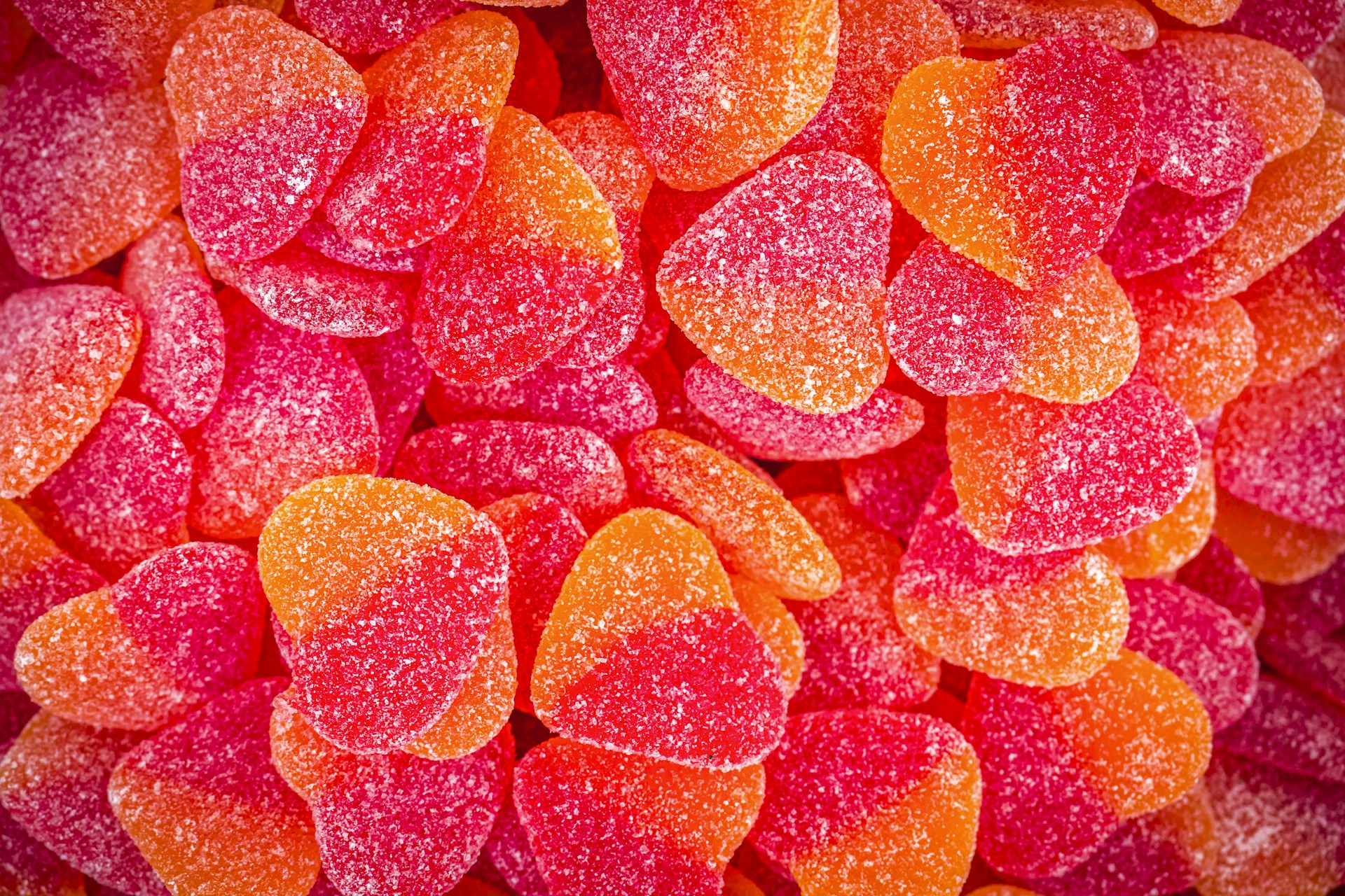 Close-up of vibrant, fun-shaped jelly candies in bright colors, glistening under soft light.
