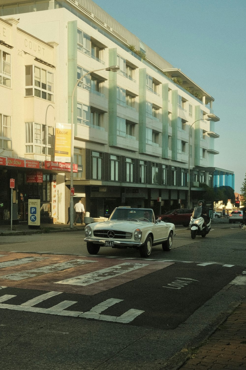 a white car driving down a street next to tall buildings