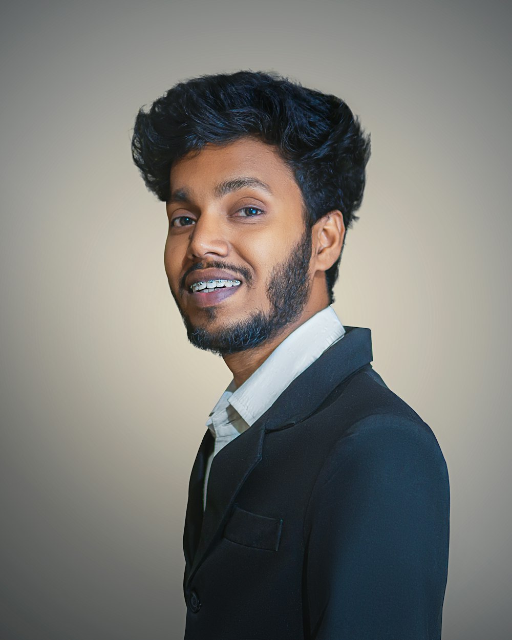 a man with black hair and a beard smiling