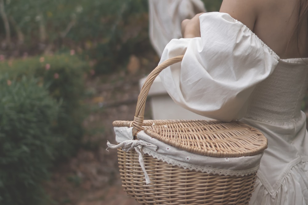a woman in a white dress carrying a wicker basket