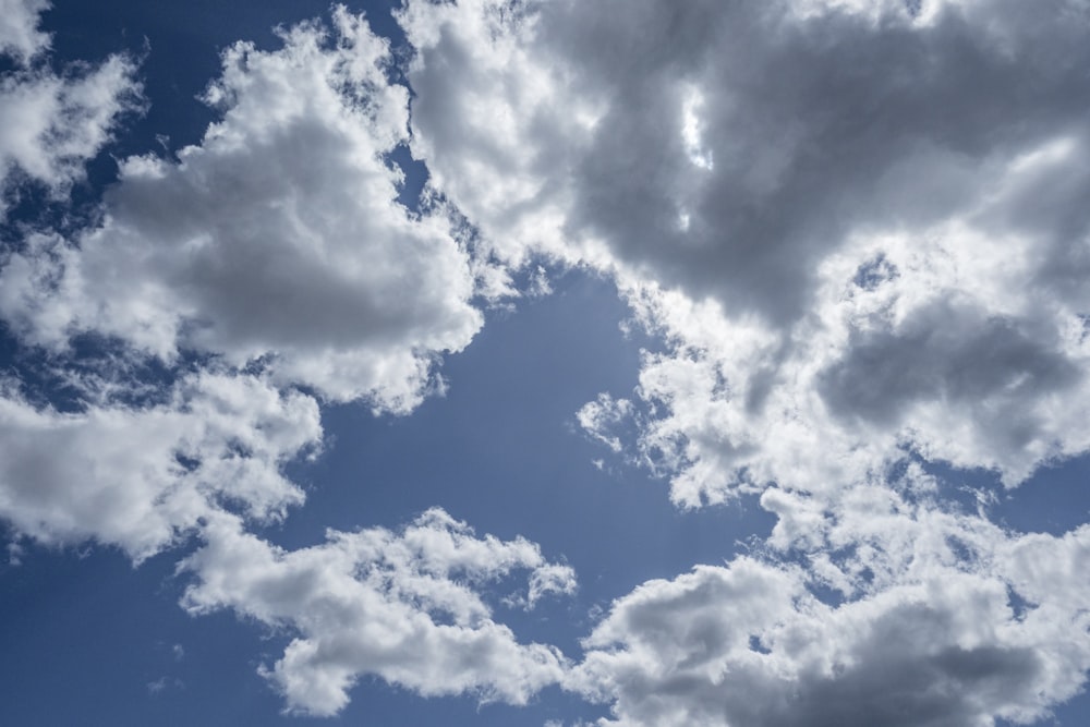 a plane flying through a cloudy blue sky