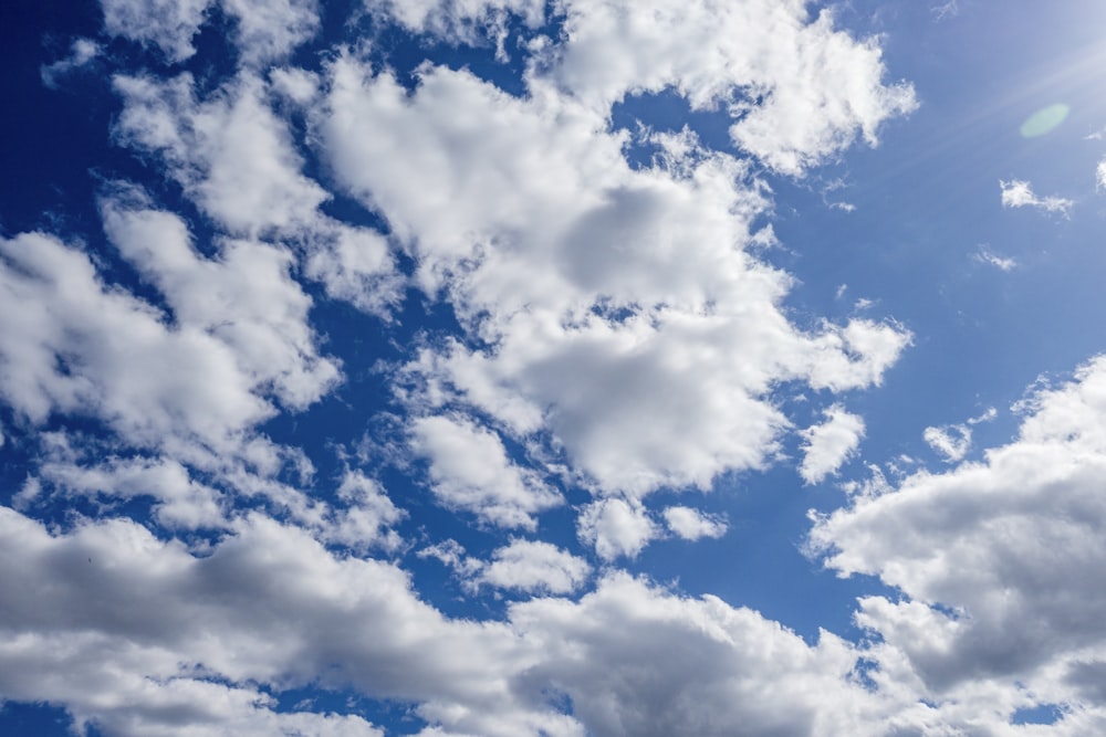 a plane flying through a blue cloudy sky